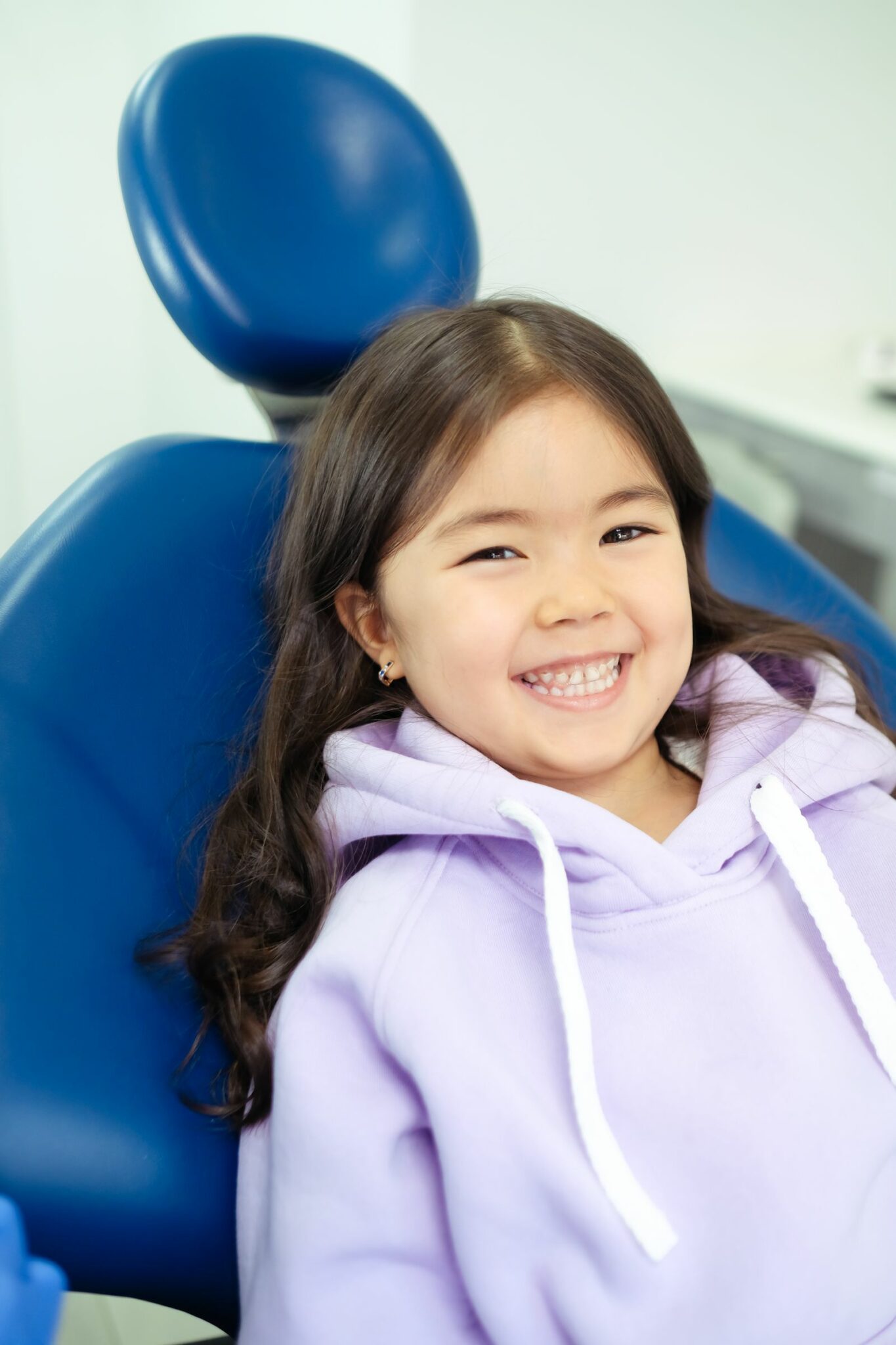 Petite fille souriante installée dans un fauteuil de soins dentaires